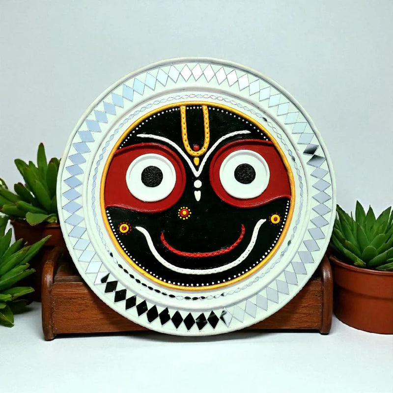Lippan Art wall decor featuring a handcrafted Jagannath face design with mirror work and traditional Indian folk detailing by Artgatha.